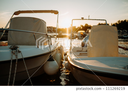 Small boats on calm water, moored in the harbor during sunset. Small boats on calm water, moored in the harbor during sunset. 111269219