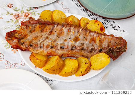 Grilled pork ribs with vegetable garnish of baked potatoes 111269233