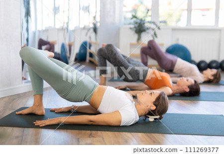 Young female yoga instructor leading group training for women in studio 111269377
