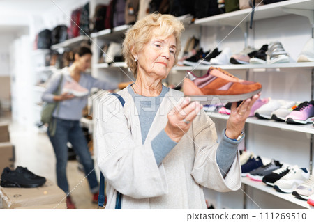 Mature european woman chooses sports sneakers 111269510