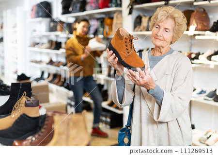 Focused mature woman chooses shoes in the Timberland style 111269513