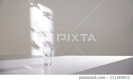 A water cup and shadow on a table in the sunlight. A water cup and shadow on a table in the sunlight. 111269652