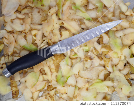 Top view of a knife lying on potato peelings 111270074