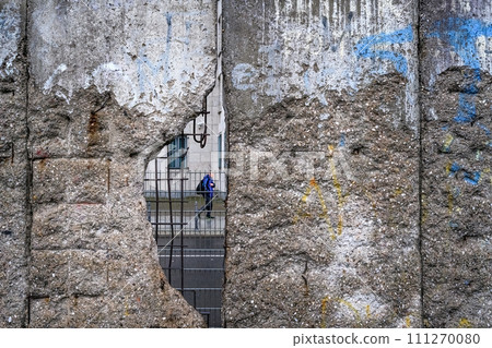 Hole in Broken Berlin wall and walking person against Hole in Broken Berlin wall and walking person against 111270080
