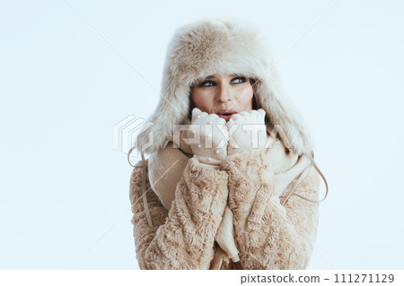 smiling modern woman warming hands with breath on white 111271129