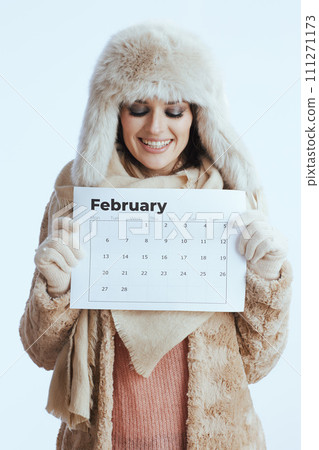 smiling woman in winter coat and fur hat on white 111271173
