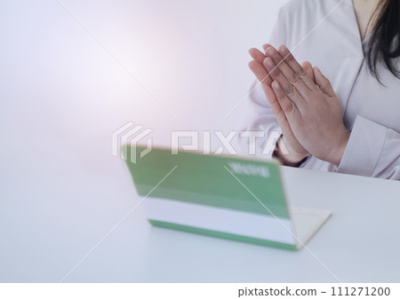 A woman looking at her bankbook and putting her hands together A woman looking at her bankbook and putting her hands together 111271200