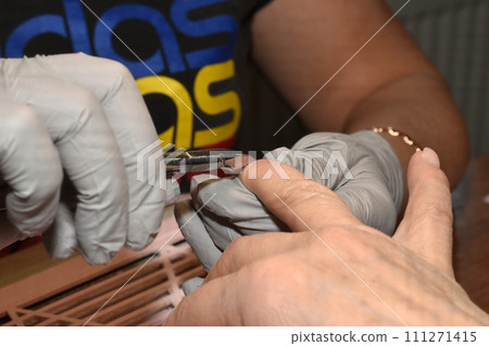 A manicurist removes cuticles with pliers. 111271415