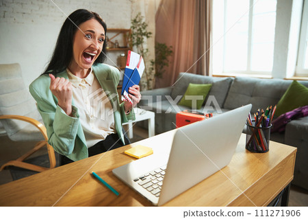 Happy, emotional businesswoman sitting in her office, talking on video call and showing plane tickets. Long awaited vacation Happy, emotional businesswoman sitting in her office, talking on video call and showing plane tickets. Long awaited vacation 111271906