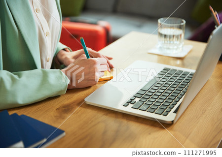 Cropped image. Focus on female hands making notes about hotel and tours. Planning vacation with online services, choosing trips and accommodation Cropped image. Focus on female hands making notes about hotel and tours. Planning vacation with online services, choosing trips and accommodation 111271995