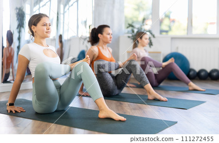 Girl teacher lead lesson, run training in female yoga studio and performs lying pigeon pose. Girl teacher lead lesson, run training in female yoga studio and performs lying pigeon pose. 111272455