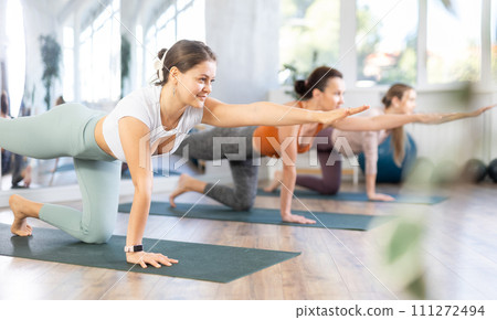 Girl teacher lead lesson, run training in female yoga studio and performs Balancing Table pose. 111272494