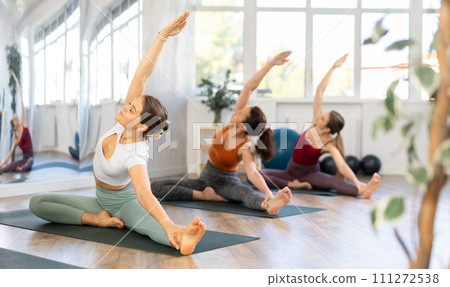 Young female yoga instructor leading group training for women in studio Young female yoga instructor leading group training for women in studio 111272538
