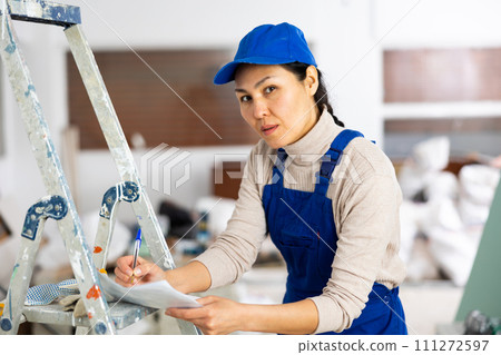 Woman builder filling project documentation 111272597
