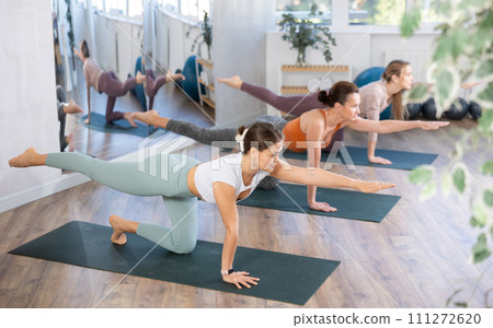 Girl teacher lead lesson, run training in female yoga studio and performs Balancing Table pose. 111272620