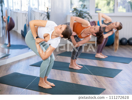 Woman performing Parivrtta Utkatasana during group yoga class 111272628
