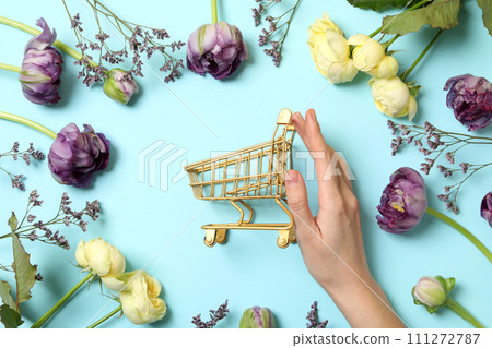 Shopping cart with flowers on a light background. 111272787