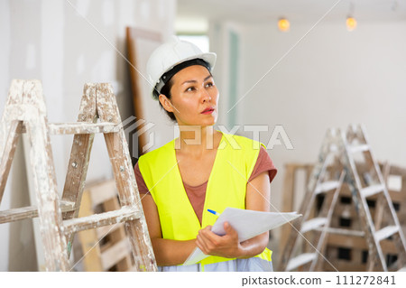 Woman engineer checking documents during repair works Woman engineer checking documents during repair works 111272841