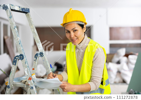 Woman in overalls signs an act of acceptance of completed work Woman in overalls signs an act of acceptance of completed work 111272878