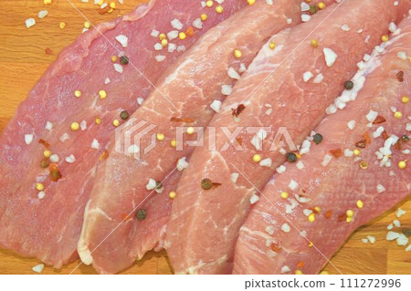 Pork chops with spices on a cutting board. Slices of pork steaks. Pork chops ready to fry. Selective focus Pork chops with spices on a cutting board. Slices of pork steaks. Pork chops ready to fry. Selective focus 111272996