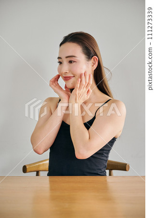 A woman in her 30s taking care of her skin by massaging her face A woman in her 30s taking care of her skin by massaging her face 111273339