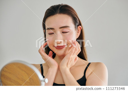 A woman in her 30s taking care of her skin by massaging her face 111273346