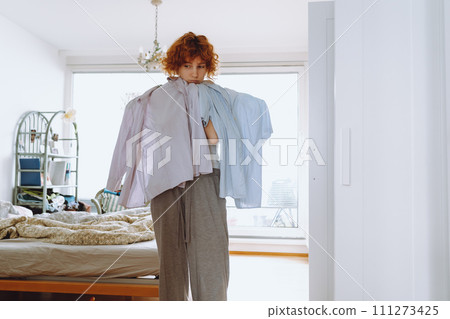 Teenager girl looking at clothes in wardrobe Teenager girl looking at clothes in wardrobe 111273425