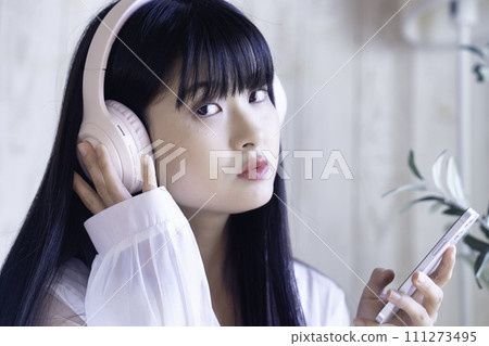 Young woman listening to music on smartphone with headphones 111273495