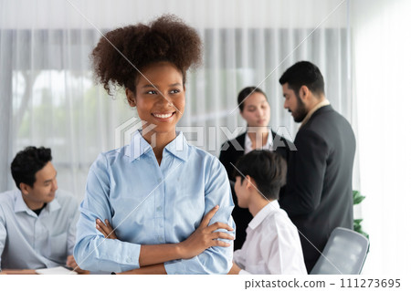 Young African businesswoman poses confidently in busy meeting room. Concord 111273695