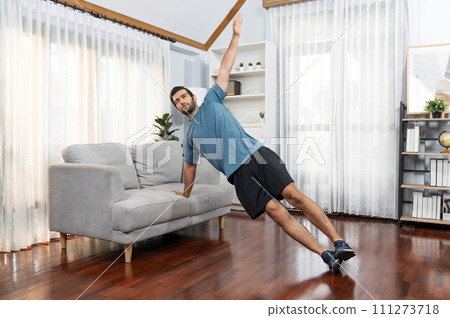 Athletic body and active sporty man using furniture for gaiety home exercise. 111273718