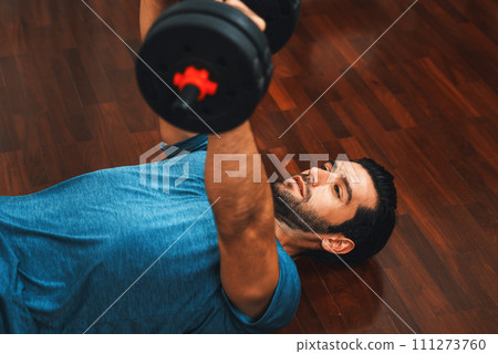 Athletic body and active sporty man lifting dumbbell at gaiety home exercise. 111273760