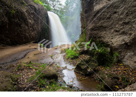 Scenery view of Blawan waterfall located in Kalianyar village, Sempol district of East Java, Indonesia. Blawan waterfall is surrounded by sharp cliffs and there is also stalagmite cave. Scenery view of Blawan waterfall located in Kalianyar village, Sempol district of East Java, Indonesia. Blawan waterfall is surrounded by sharp cliffs and there is also stalagmite cave. 111273787