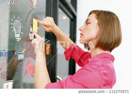 Young beautiful businesswoman putting sticker on glass board. Immaculate. 111273871