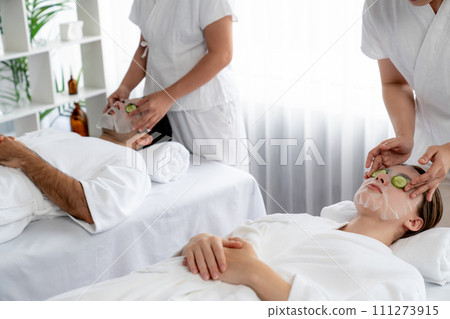 Couple customer indulges in rejuvenating with cucumber facial care. Quiescent 111273915