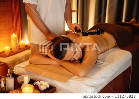 Hot stone massage at spa salon in luxury resort with warm candle light.Quiescent 111273928