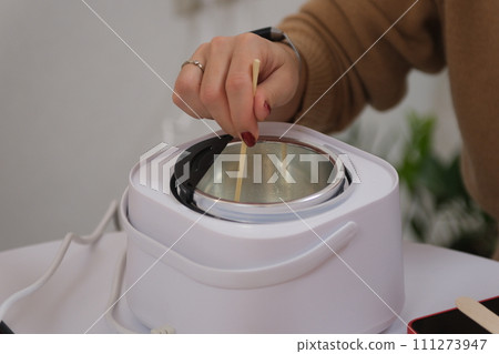 The process of making a massage candle using ingredients oils and wax measure weigh stir add close-up of women's hands. food thermometer measure wax temperature women's party women witches witchcraft The process of making a massage candle using ingredients oils and wax measure weigh stir add close-up of women's hands. food thermometer measure wax temperature women's party women witches witchcraft 111273947