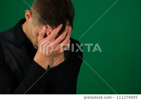 emotions of a handsome man guy on a green background chromakey close-up dark hair young man European teenager boy dressed in a black T-shirt is worried and holds his head emotions of a handsome man guy on a green background chromakey close-up dark hair young man European teenager boy dressed in a black T-shirt is worried and holds his head 111274005