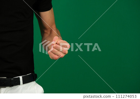 close-up on a green background clenched fist man aggression dissatisfaction space for text expression of negative emotions white jeans black T-shirt unrecognizable people guy chromakey close-up on a green background clenched fist man aggression dissatisfaction space for text expression of negative emotions white jeans black T-shirt unrecognizable people guy chromakey 111274053