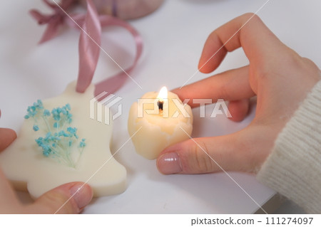 The process of making a massage candle using ingredients oils and wax measure weigh stir add close-up of women's hands. food thermometer measure wax temperature women's party women witches witchcraft 111274097