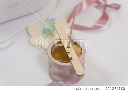 The process of making a massage candle using ingredients oils and wax measure weigh stir add close-up of women's hands. food thermometer measure wax temperature women's party women witches witchcraft The process of making a massage candle using ingredients oils and wax measure weigh stir add close-up of women's hands. food thermometer measure wax temperature women's party women witches witchcraft 111274180