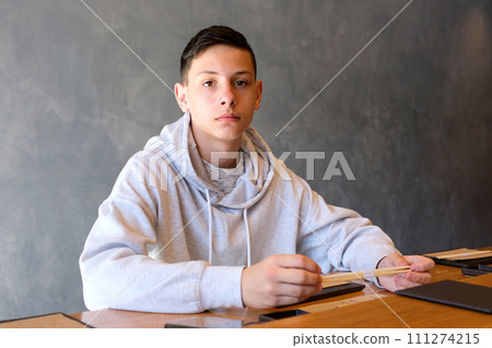 Tired from study a student boy is sitting by the school desk. 111274215