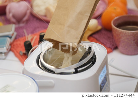 The process of making a massage candle using ingredients oils and wax measure weigh stir add close-up of women's hands. food thermometer measure wax temperature women's party women witches witchcraft 111274444