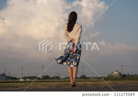 夏日傍晚，一個女人望著雲彩的後視圖 111275084
