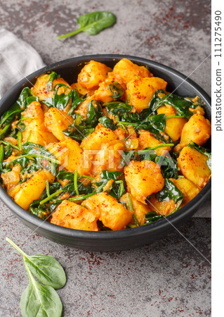 Spiced curry dish made with potatoes and spinach saag aloo closeup on the plate. Vertical 111275490