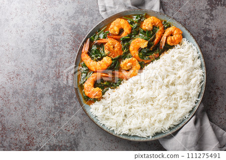 Palak Prawn made of spinach, cream, spices, tomato and ginger served with rice closeup on the plate. Horizontal top view Palak Prawn made of spinach, cream, spices, tomato and ginger served with rice closeup on the plate. Horizontal top view 111275491