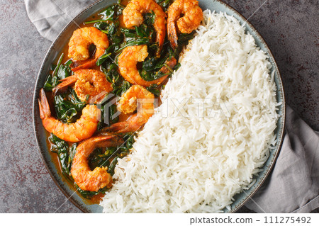 Spinach Shrimp Curry or Jheenga Palak cooked in a spinach, cream, spices, tomato and ginger served with rice closeup on the plate. Horizontal top view Spinach Shrimp Curry or Jheenga Palak cooked in a spinach, cream, spices, tomato and ginger served with rice closeup on the plate. Horizontal top view 111275492