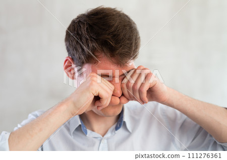 Man scretching itchy eyes on gray background Man scretching itchy eyes on gray background 111276361