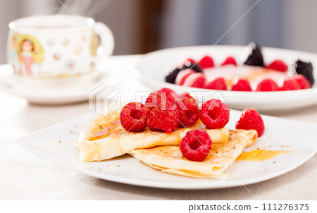 Breakfast of pancakes with fresh raspberries on table Breakfast of pancakes with fresh raspberries on table 111276375