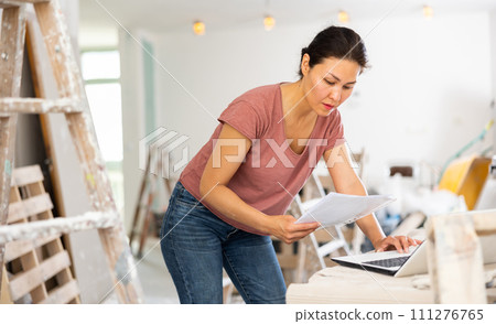 Female architect using laptop during repair works Female architect using laptop during repair works 111276765