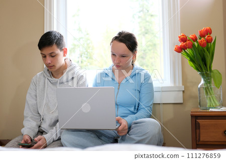 Two caucasian children watching something funny on laptop. Attractive brunette boy pointing his hand on screen. Pretty little girl laughing from what she see on computer Two caucasian children watching something funny on laptop. Attractive brunette boy pointing his hand on screen. Pretty little girl laughing from what she see on computer 111276859